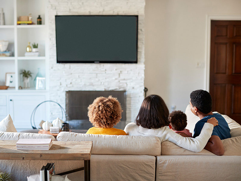 family-on-couch-looking-at-tv-mounted-on-wall-of-living-room-nampa-id